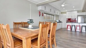 A modern kitchen with white cabinets, a wooden dining table with chairs, and a red countertop.