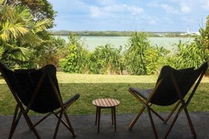 Due sedie e un tavolino su una terrazza con vista su un lago e sulla vegetazione.