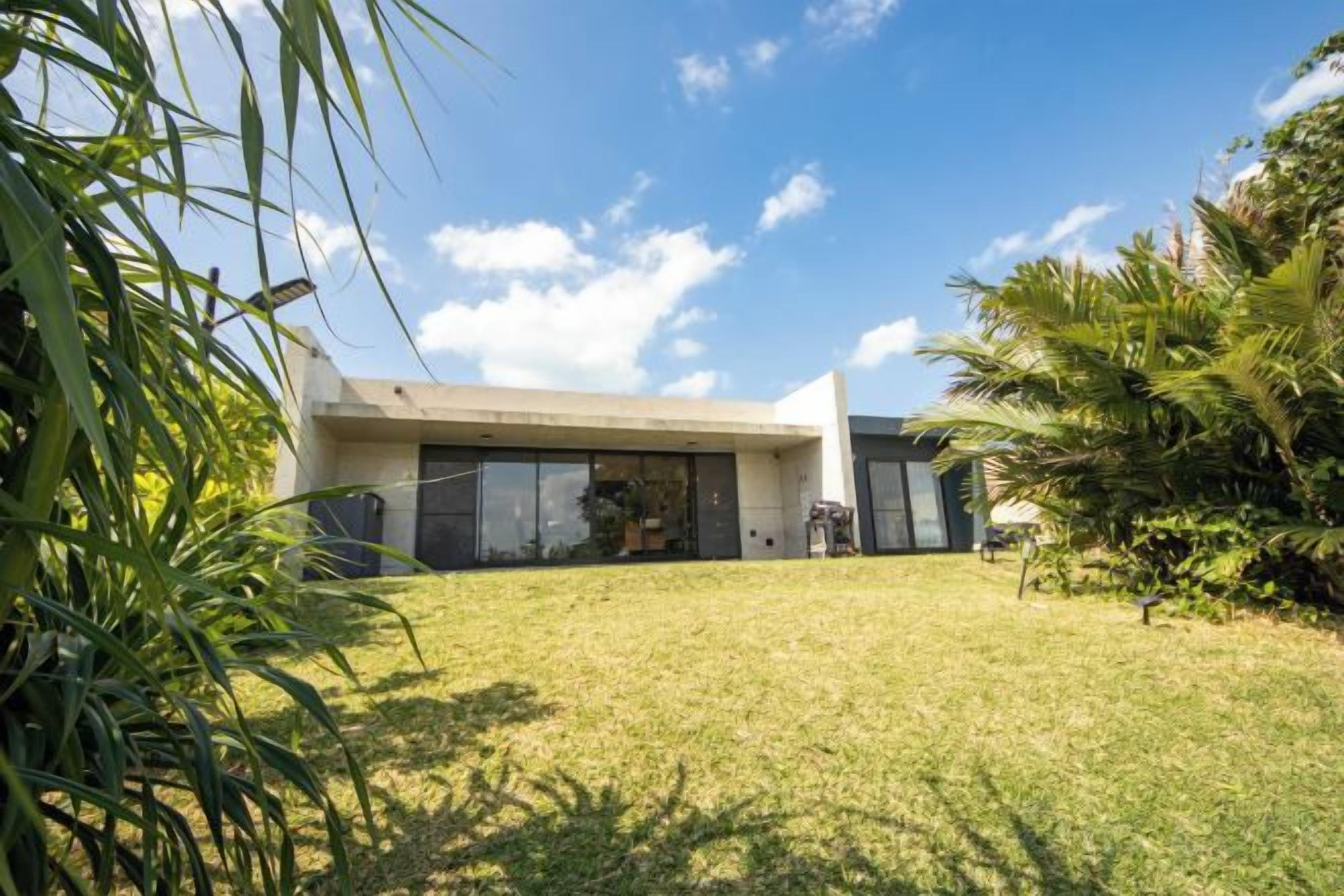 Una casa moderna con techo plano, ventanas amplias y un césped cuidado.