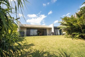 A modern house with a flat roof, large windows, and a well-maintained lawn.