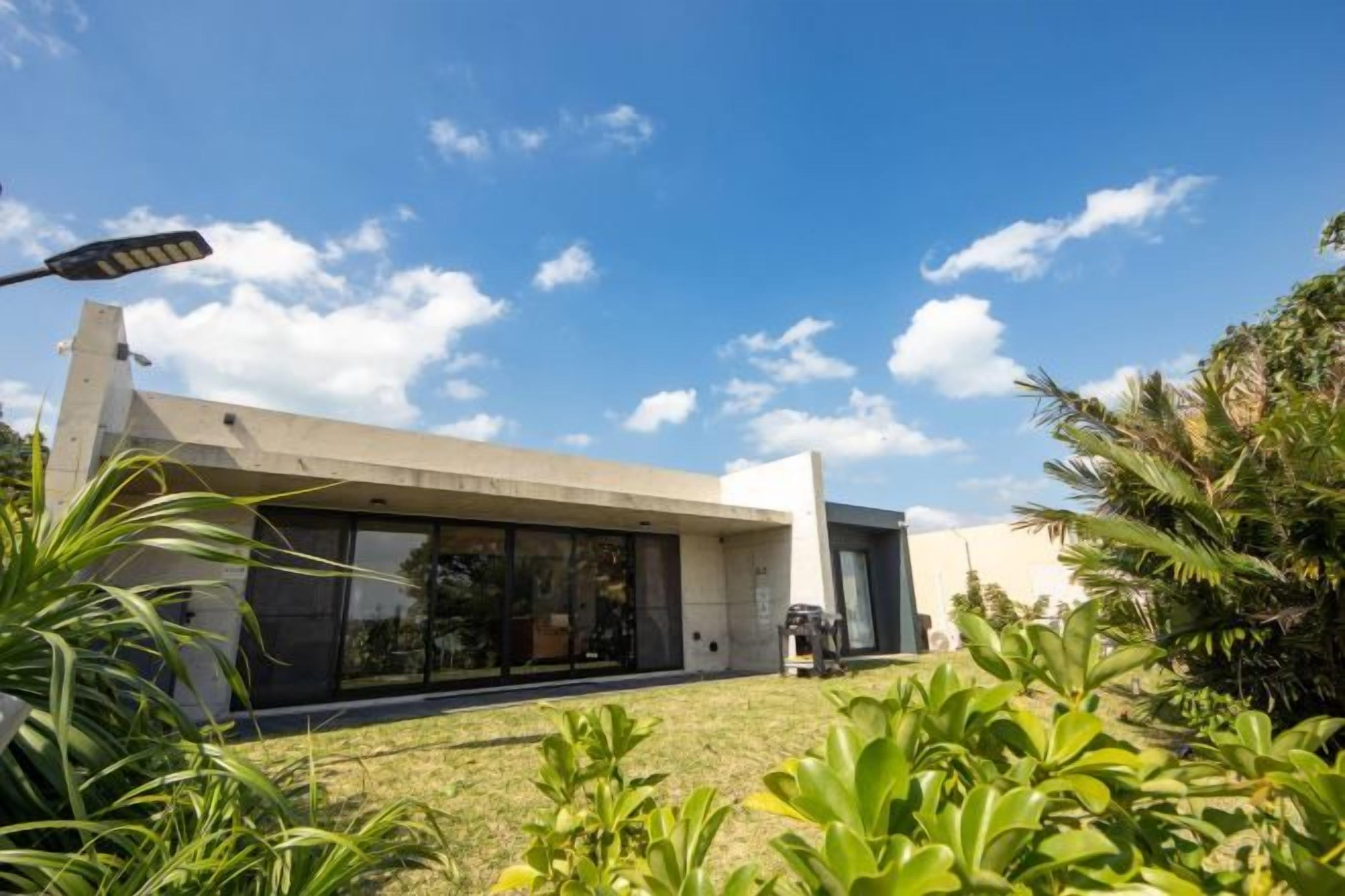 Una casa moderna con techo plano, ventanas amplias y un césped bien cuidado.