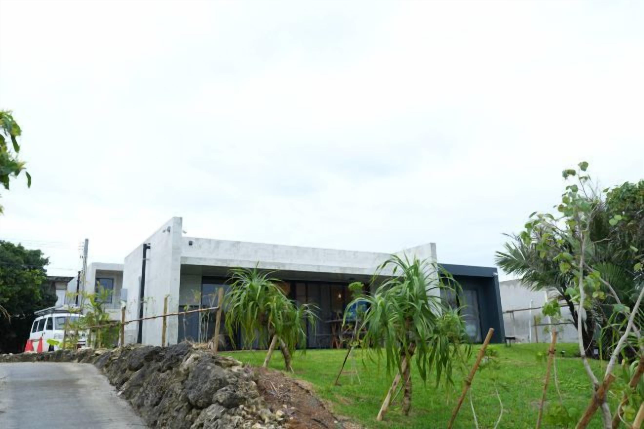 Un edificio moderno con techo plano, fachada de concreto y camino de entrada pavimentado.