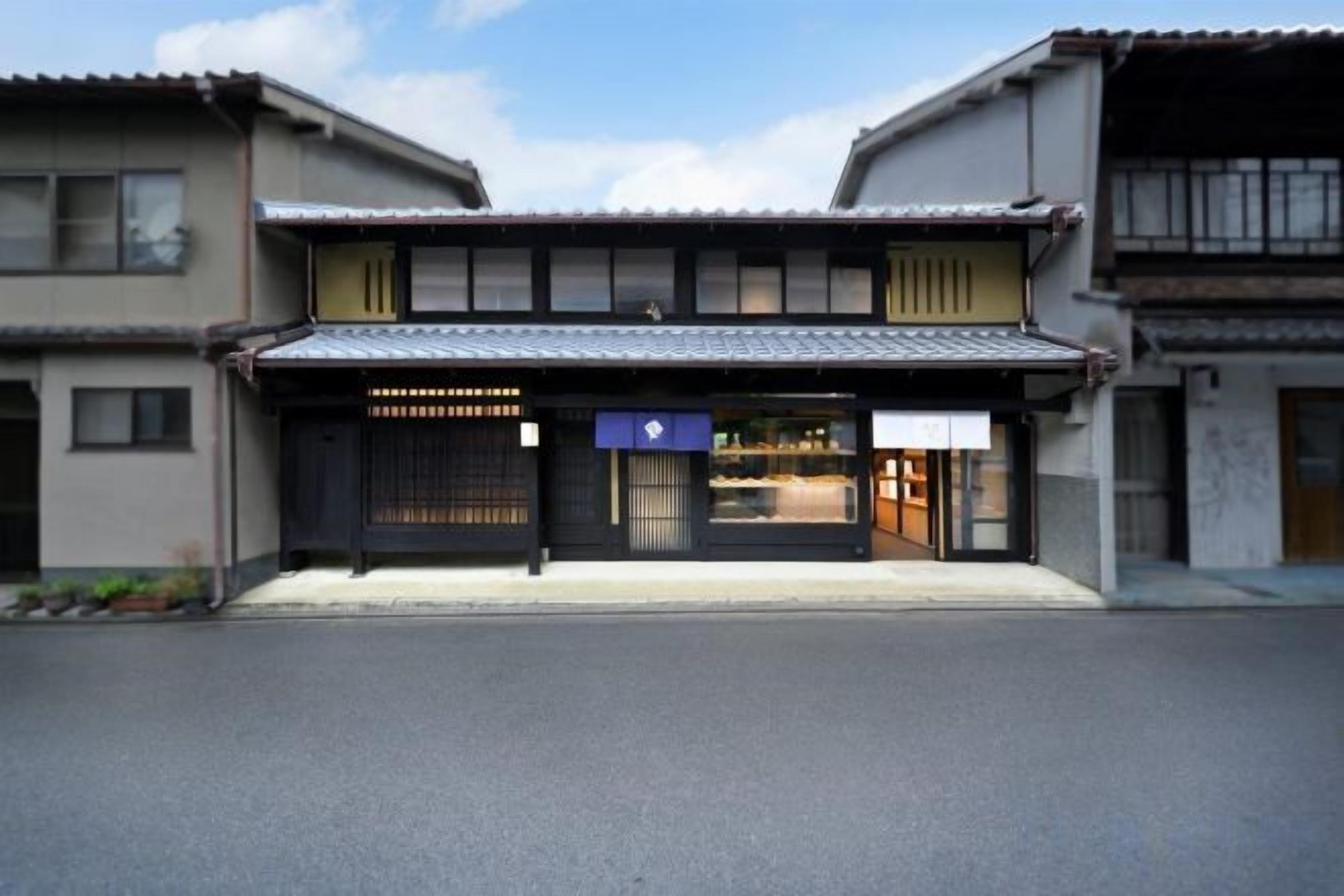 A traditional Japanese building with a covered entrance, a visible shop, and a clear sky.