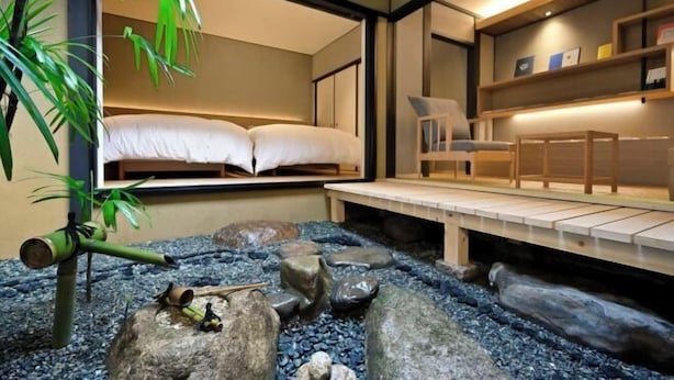 Une pièce comprenant un lit, un bureau et un petit jardin intérieur agrémenté de rochers et de plantes.
