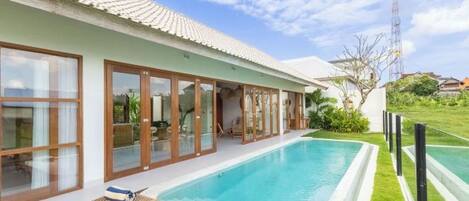 Una casa moderna con piscina, ventanas amplias y jardín.