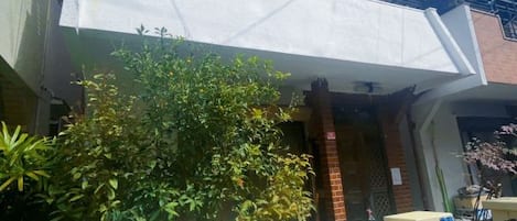 Un edificio residencial con techo plano, entrada de ladrillo y un pequeño jardín.
