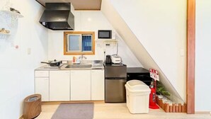 A compact kitchen with a microwave, stove, and sink. - He Sheng Shi Guang101 (Osaka)