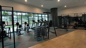 A gym with cardio machines, weight stations, and a large window providing natural light. - Datum Jelatek Superb Suite KL By LH (Ampang)