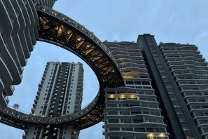 Een rond architectonisch element met een modern ontwerp, omringd door hoogbouw.