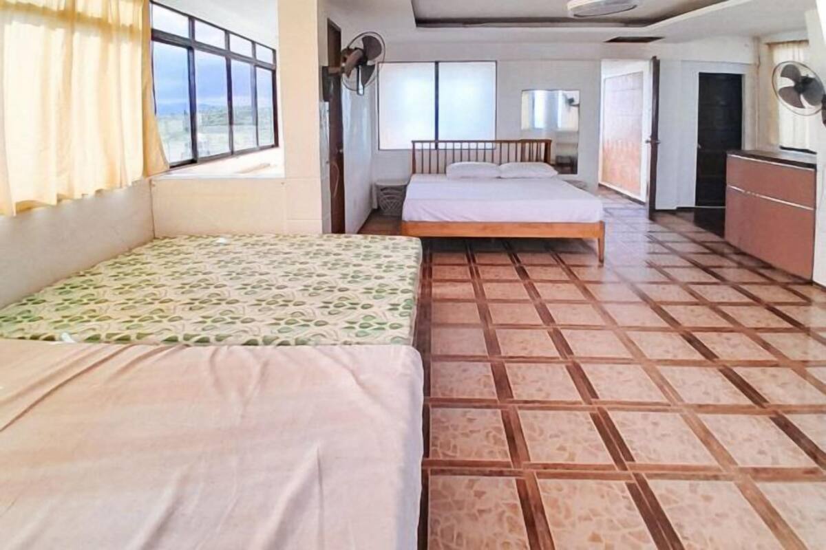 A room with two beds, a tiled floor, a desk, and a window.