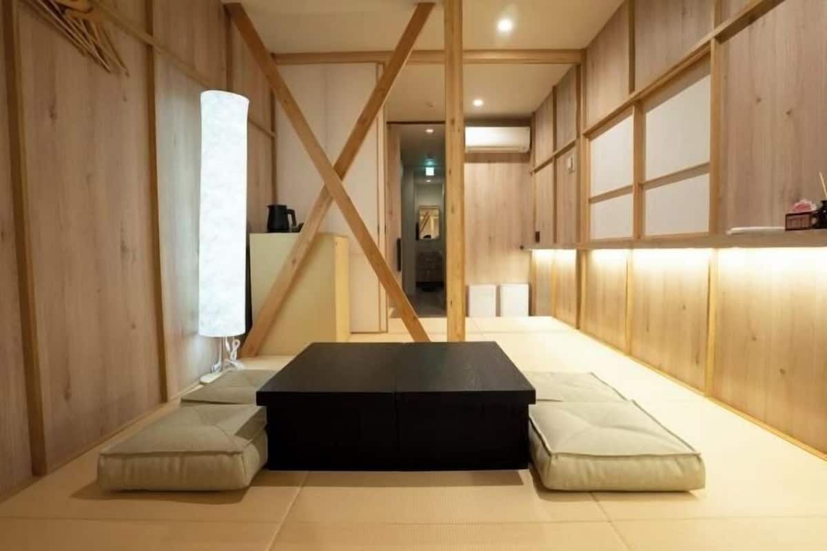 A room with tatami flooring, a black rectangular table, and cushions.