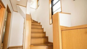 A wooden staircase with a handrail, leading to a landing with a window. - Sakura Retreat (Tokyo)