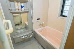A compact bathroom with a sink, mirror, and a bathtub.