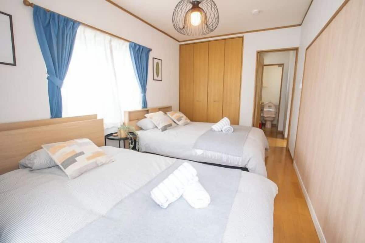 A hotel room with two beds, a wooden wardrobe, a ceiling light fixture, and a mirror.