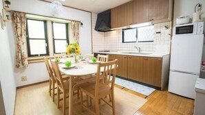 A compact kitchen with wooden cabinets, a white countertop, and a built-in microwave. - Sakura Retreat (Tokyo)
