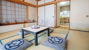 A traditional Japanese room with tatami flooring, a low table with a tray of items, and sliding doors. - Sakura Retreat (Tokyo)