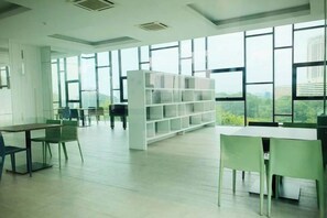 A spacious room with large windows, a white bookshelf, and green chairs. - Delight Homestay Mosaic Southkey (Plentong)