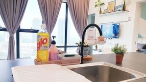A modern kitchen with a stainless steel sink, a bottle of dish soap, and a dish rack. - Delight Homestay Mosaic Southkey (Plentong)