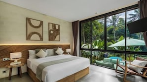 A modern bedroom with a large bed, a wooden headboard, a nightstand, and a view of lush greenery through large windows. - Villa Dream Life by BaliSuperHost (Bali)