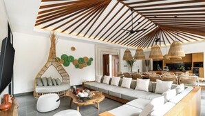 A modern living room with a high ceiling, a sofa set, a coffee table, and a wicker chair. - Villa Dream Life by BaliSuperHost (Bali)