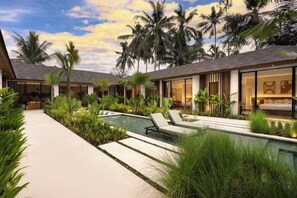 Ett semesterparadis med en swimmingpool, palmer och modern arkitektur.