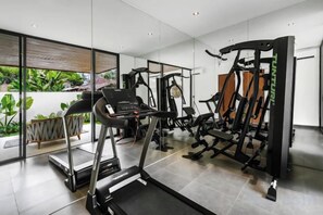Ett modernt gym med löpband, styrketräningsmaskiner och en vägg med speglar.