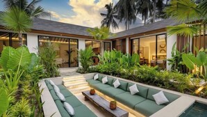 A modern outdoor living area with a pool, green seating, and tropical plants. - Villa Dream Life by BaliSuperHost (Bali)