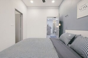 A modern bedroom with a bed, a bedside table, and a wall-mounted light fixture. - Mini House Gombak2BR 5paxAyuman Suites (Setapak)