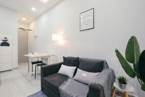 A modern living room with a grey sofa, a small table, and a potted plant. - Mini House Gombak2BR 5paxAyuman Suites (Setapak)