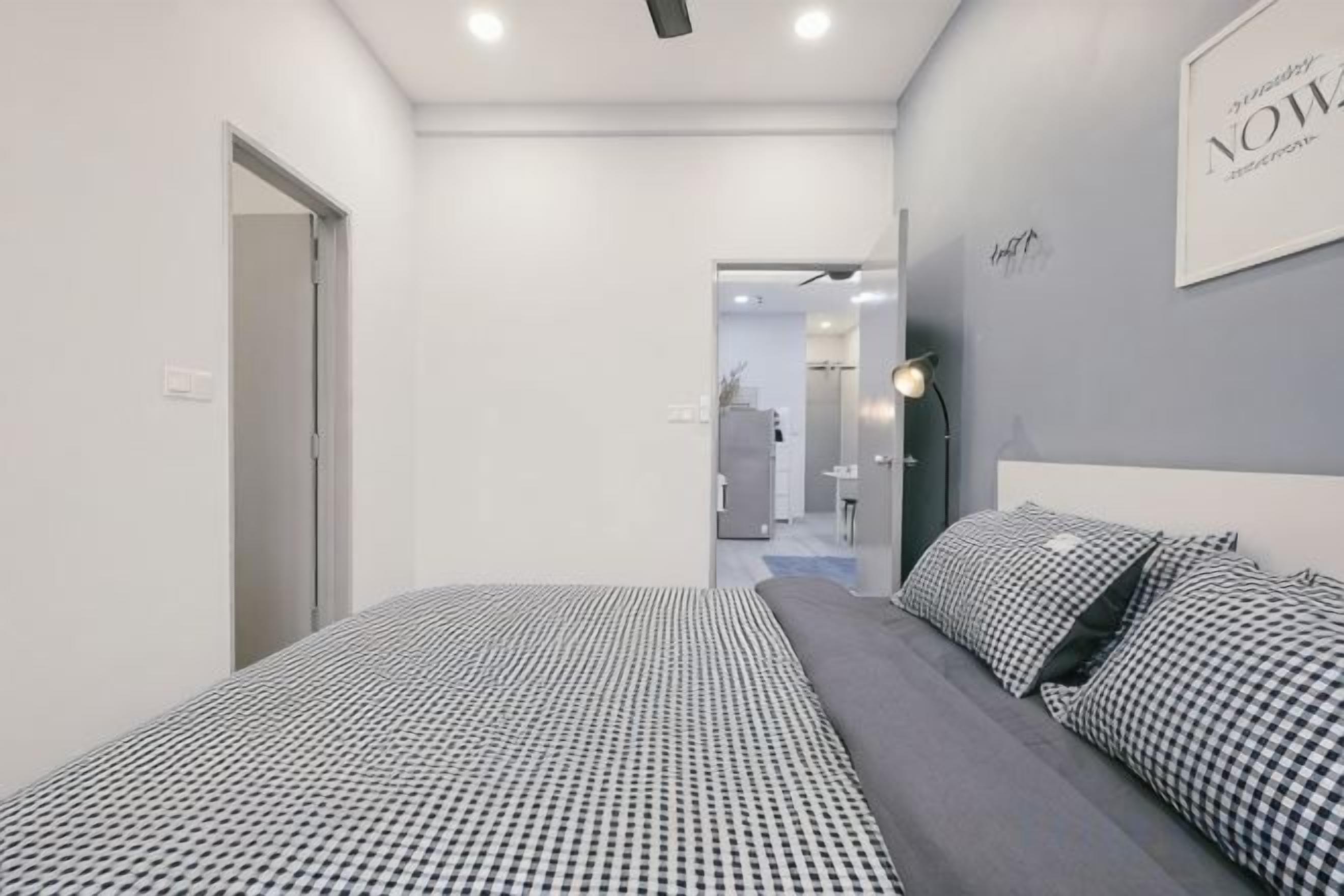 A modern bedroom with a bed, a bedside table, and a wall-mounted light fixture.
