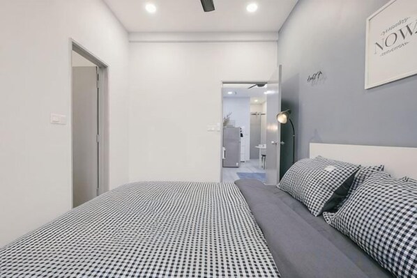 A modern bedroom with a bed, a bedside table, and a wall-mounted light fixture.