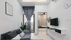 A modern living room with a grey sofa, a flat-screen TV, a white console table, and a large window with curtains. - Mini House Gombak2BR 5paxAyuman Suites (Setapak)
