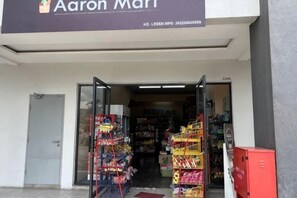 Ein Laden Eingang mit einem Schild, auf dem 'Aaron Mart' steht, und einem Einblick in die Warenbestände.