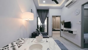 A modern living room with a dining table, sofa, TV, and a ceiling fan. - Mini House Gombak2BR 5paxAyuman Suites (Setapak)