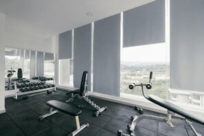 A gym with exercise equipment, large windows, and a view of the city. - Mini House Gombak2BR 5paxAyuman Suites (Setapak)
