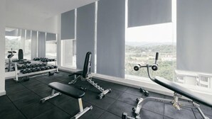 A gym with exercise equipment, large windows, and a view of the city. - Mini House Gombak2BR 5paxAyuman Suites (Setapak)