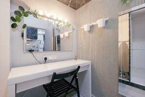 Ein Badezimmer mit weißem Waschtisch, einem beleuchteten Spiegel, einem Handtuchhalter und einer Wand mit Muster.