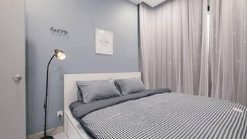 A bedroom with a bed, a bedside lamp, and a wall with a light switch.
