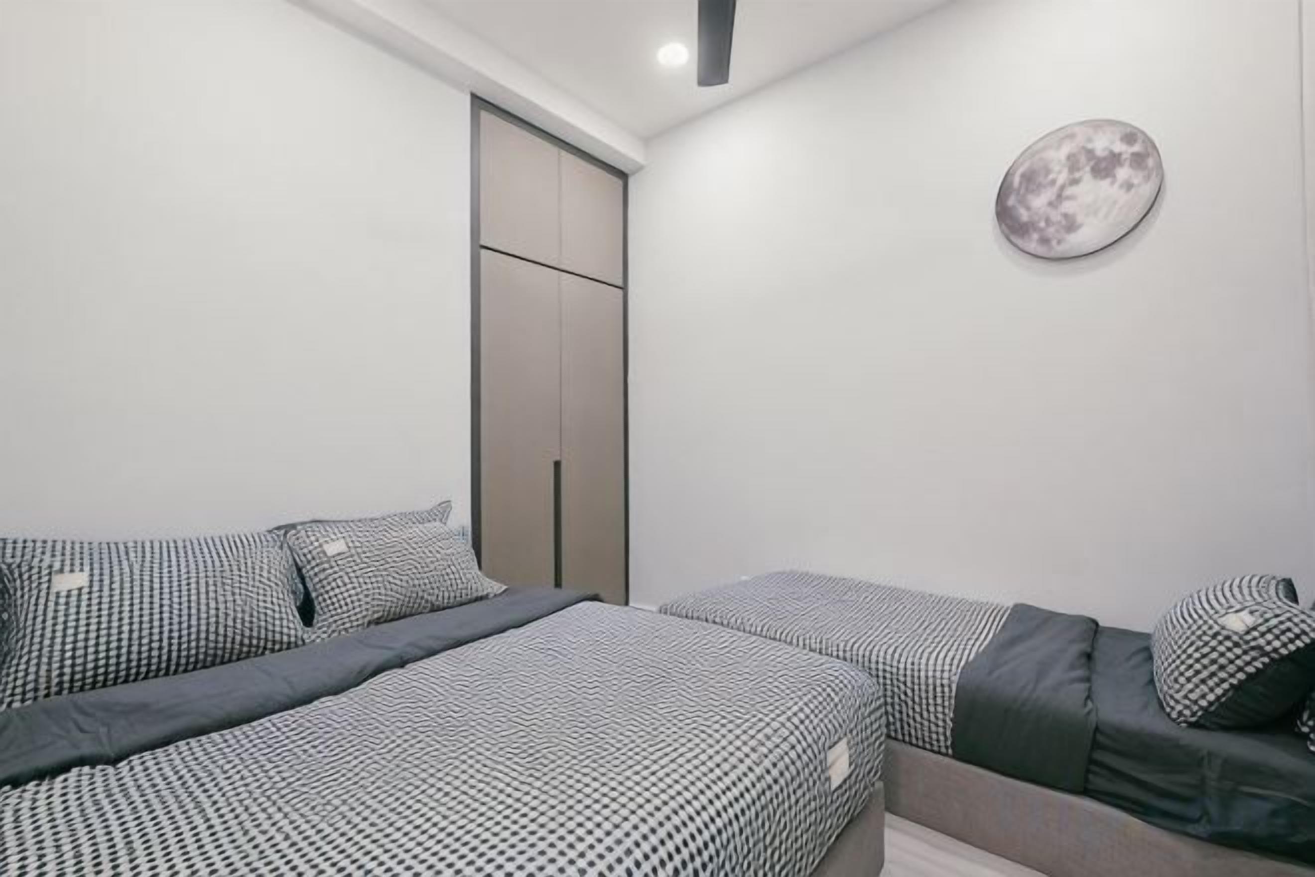 A bedroom with two beds, a wardrobe, and a wall-mounted artwork.