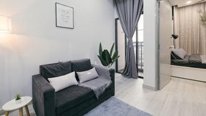A modern living room with a sofa, a small side table, a potted plant, and a view of a balcony. - Mini House Gombak2BR 5paxAyuman Suites (Setapak)