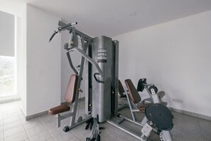 A gym with exercise machines, a bench, and a mirror. - Mini House Gombak2BR 5paxAyuman Suites (Setapak)
