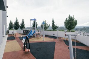 An outdoor play area with a slide, swings, and climbing structures. - Mini House Gombak2BR 5paxAyuman Suites (Setapak)