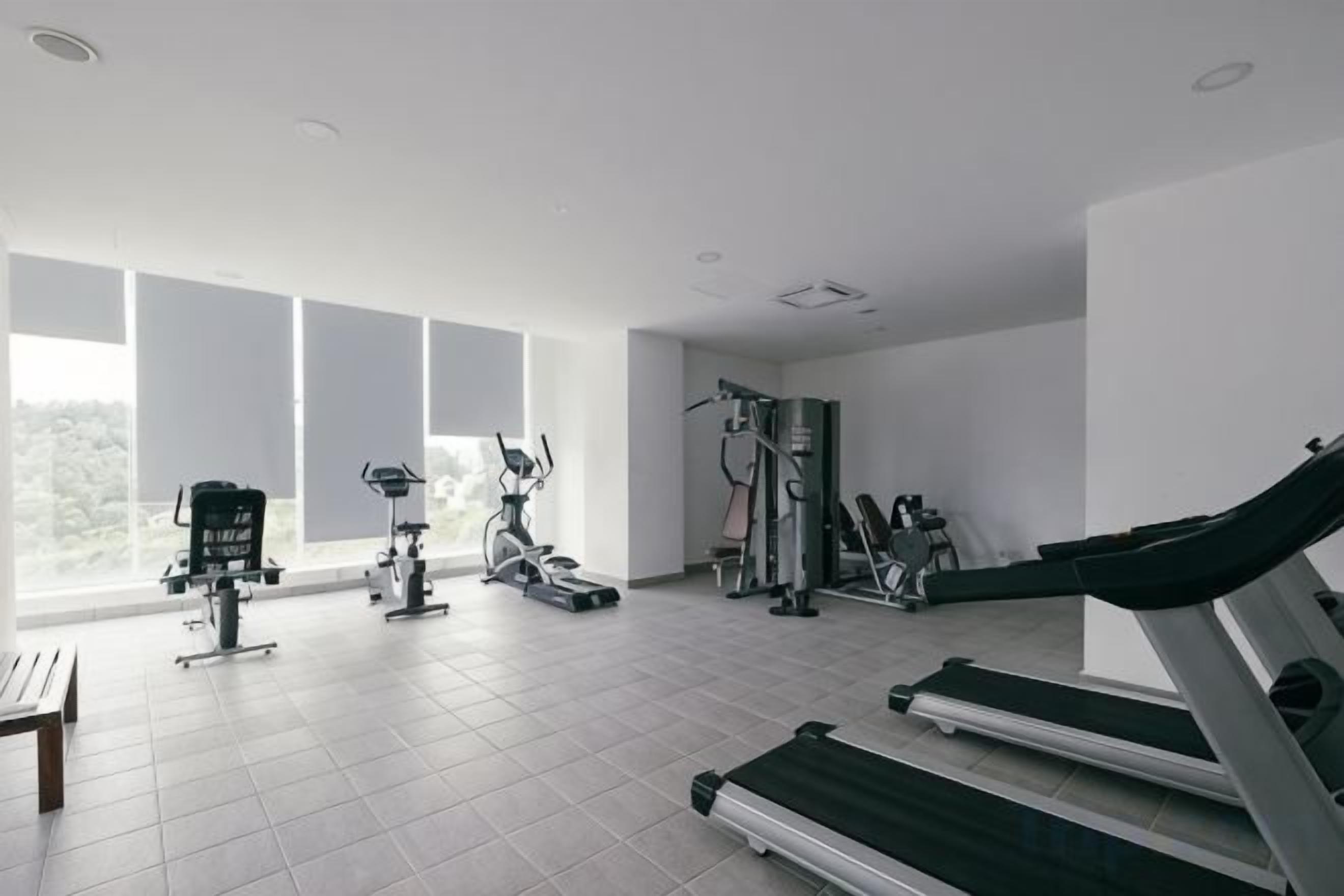 A gym with various exercise equipment, large windows, and a tiled floor.
