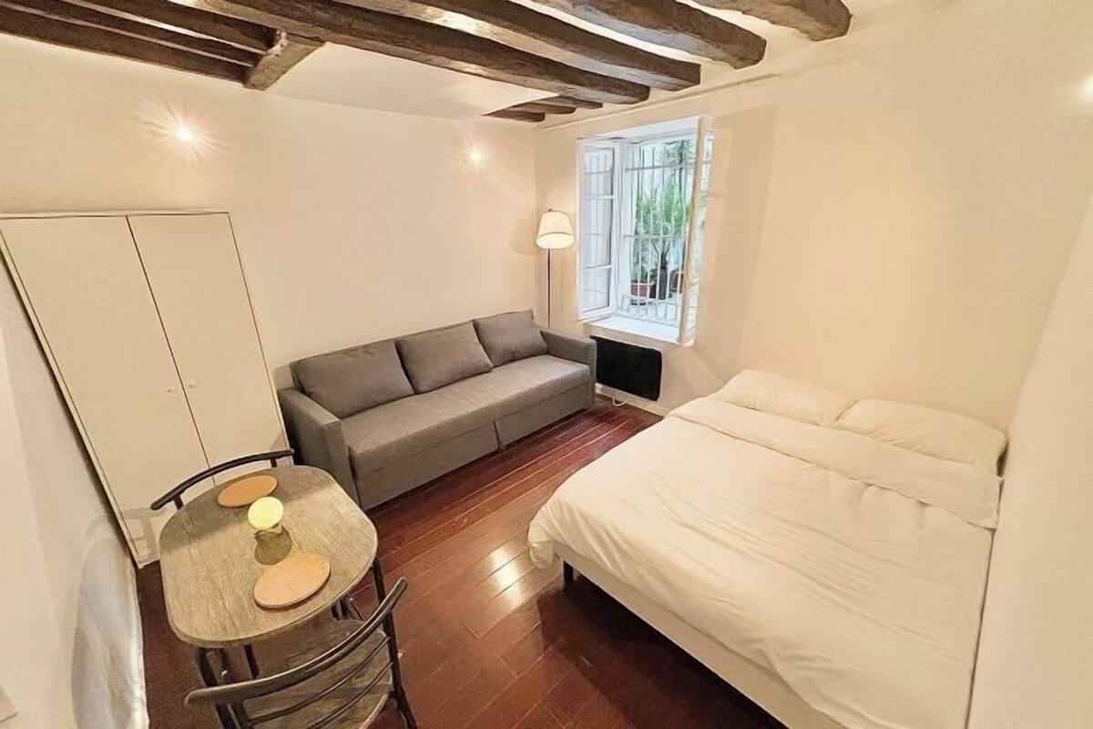 Une chambre à coucher comprenant un lit, un canapé, une table avec des chaises et une fenêtre donnant sur un paysage verdoyant.