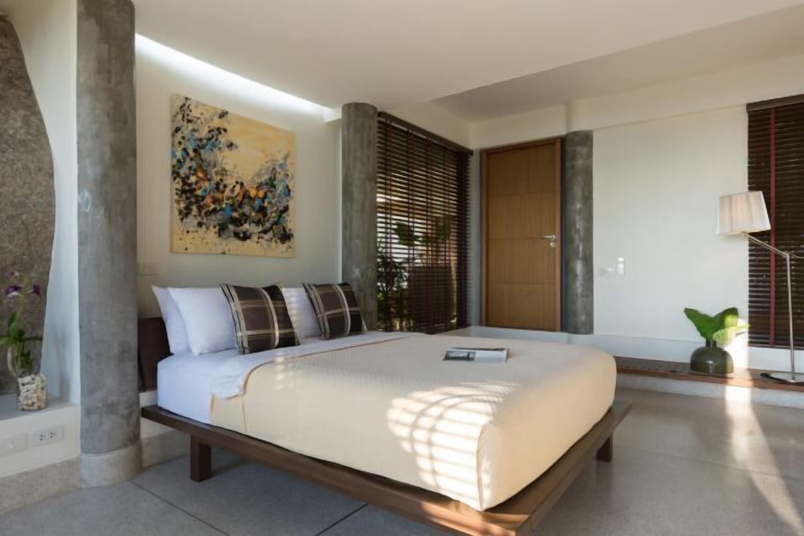 Un dormitorio moderno con cama, una obra de arte, una ventana con persianas y una planta.