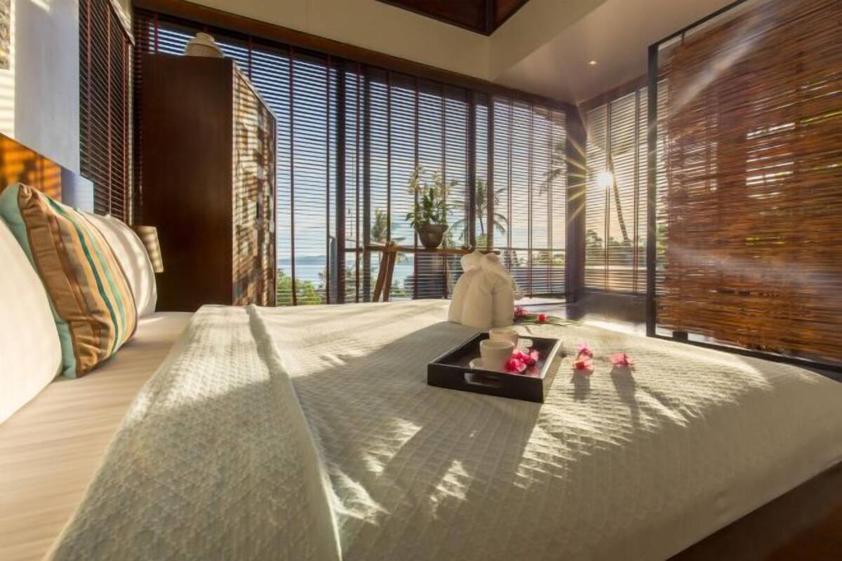 A modern room with a bed, a tray with items, and a view through large windows.