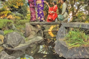 A traditional Japanese garden with a stone bridge, koi pond, and lush greenery. - Iidaya Hotel (Yokohama)