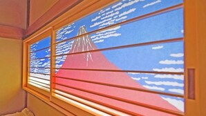 A room with a window featuring a red and blue design, possibly depicting a mountain or landscape. - Iidaya Hotel (Yokohama)