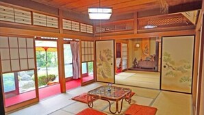 A traditional Japanese room with tatami flooring, sliding doors, and a low table with cushions. - Iidaya Hotel (Yokohama)