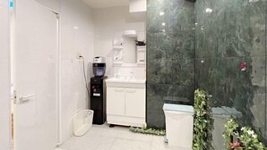 A modern bathroom with a white door, a black water dispenser, a white sink, and a green marble wall. - MIIYAVI Hotel (Tokyo)